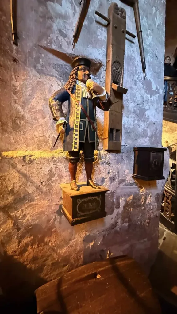 Historische Holzfigur eines Manns mit Rüstung und Federhut in einer Weinbar.