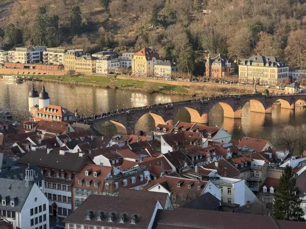 Historisches Brückenbild in Heidelberg, Deutschland, mit Fachwerkhäusern und Flusslandschaft.
