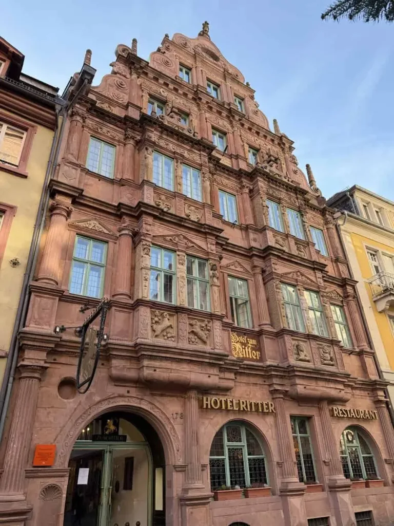 Historisches rotes Gebäude in Deutschland mit Hotel- und Restaurant-Schildern, barocke Fassadendetails und elegante Architektur.