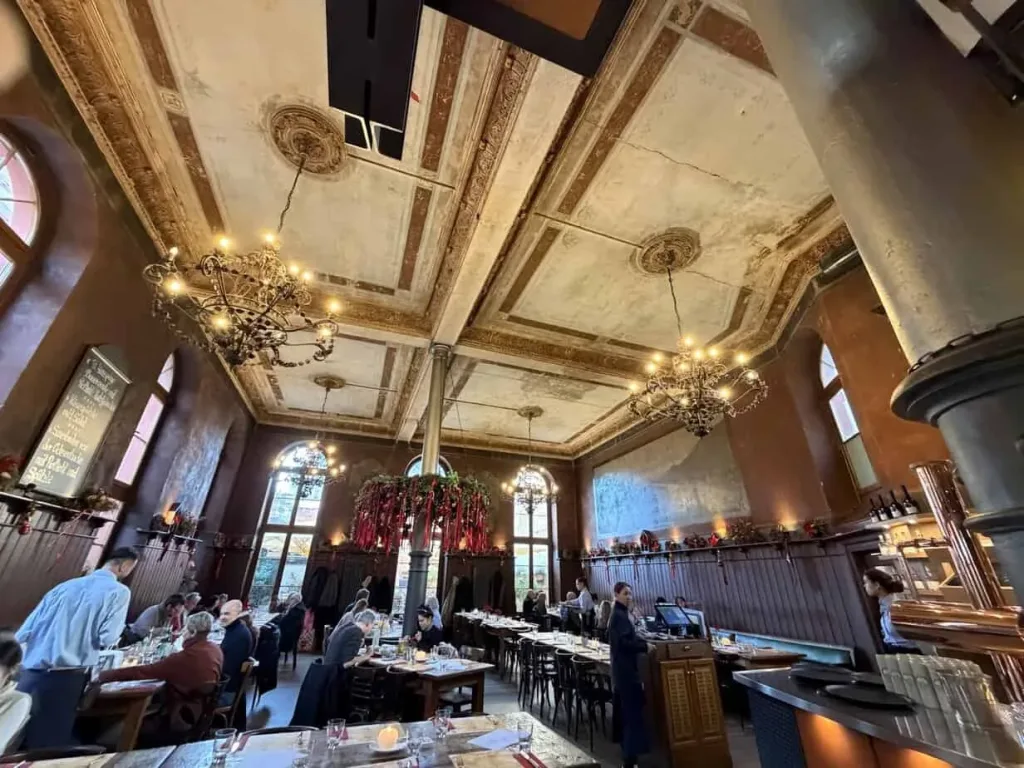 Elegantes Restaurant mit hohem Decken, Kronleuchtern und historischen Dekorelementen.