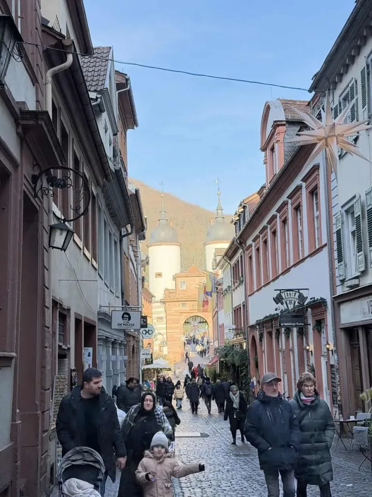 Historische Altstadt mit bunten Fassaden und Touristen in Füssen, Bayern, im Hintergrund.