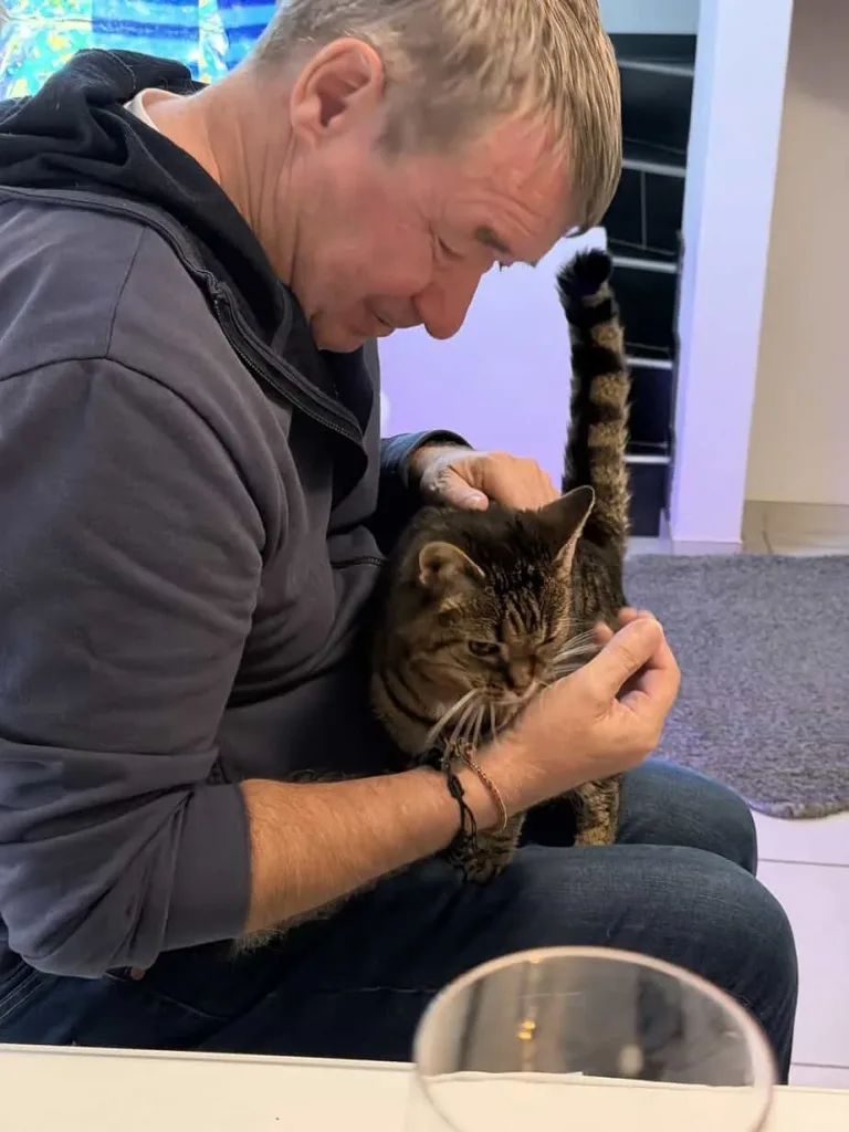 Entspannter Mann mit Katze auf dem Schoß, Tierliebe und Freundschaft.