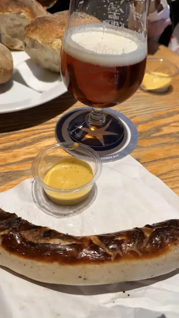 Knoblauchbrot, Bier und Senf auf einem Holztablett in einem Restaurant.