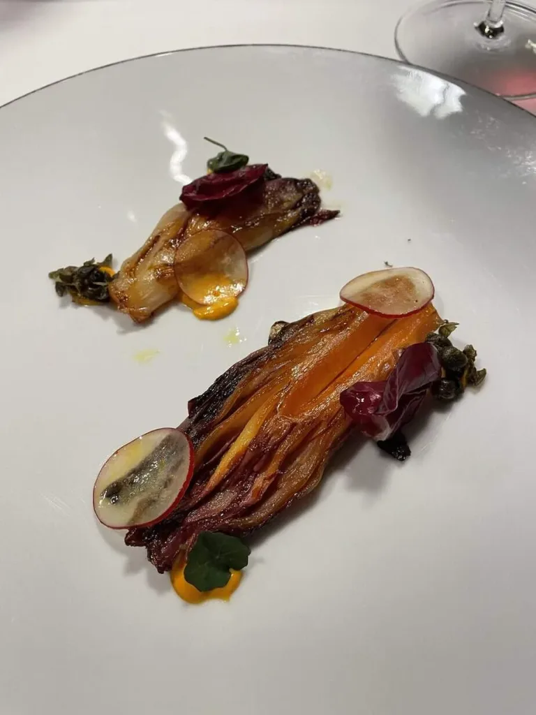 Zartes Gemüse mit hauchdünnen Radieschen und essbaren Blumen, kulinarische Kunst auf hohem Niveau.
