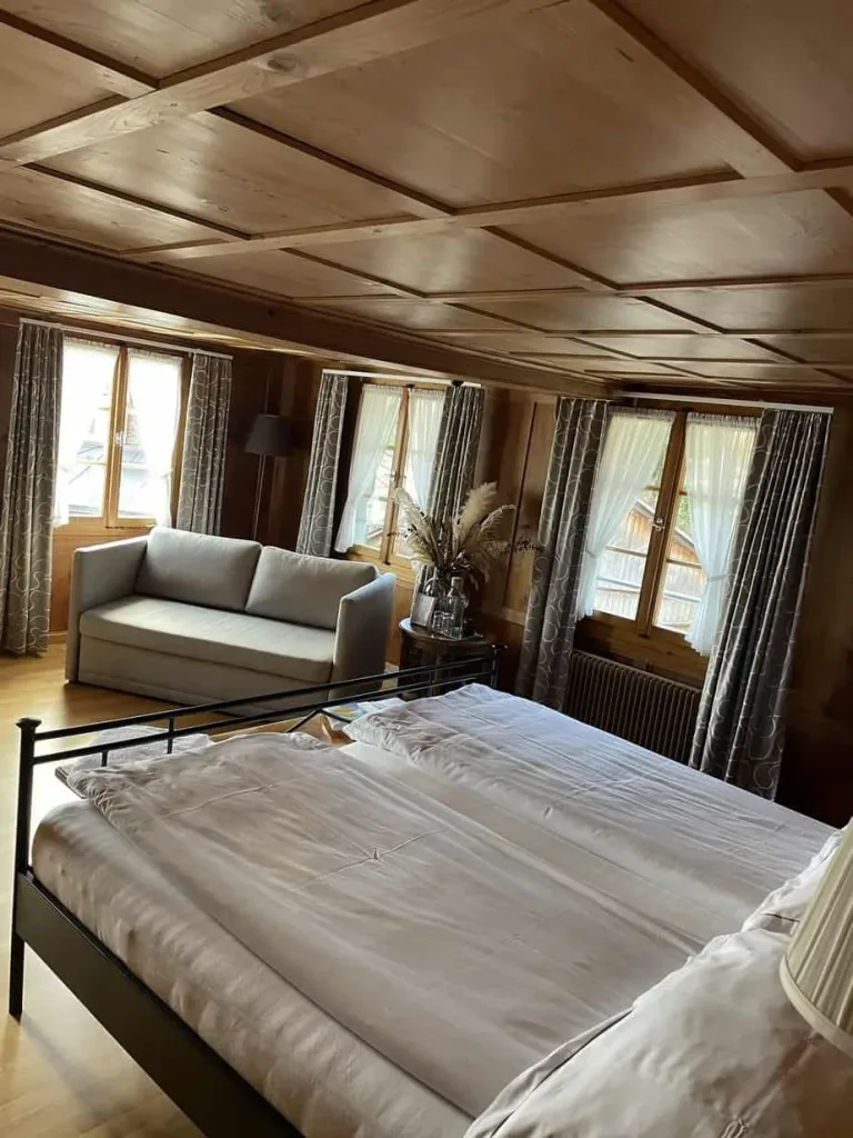 Gemütliches Schlafzimmer mit Holzmöbeln und großen Fenstern.