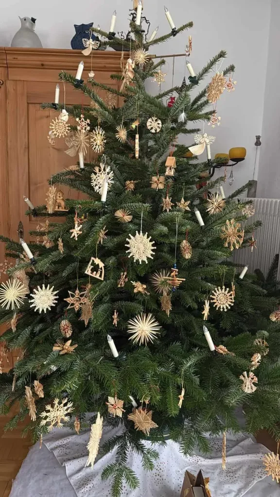 Eleganter Weihnachtsbaum mit handgefertigten Holzornamenten und Kerzen, perfekt für festliche Stimmung.