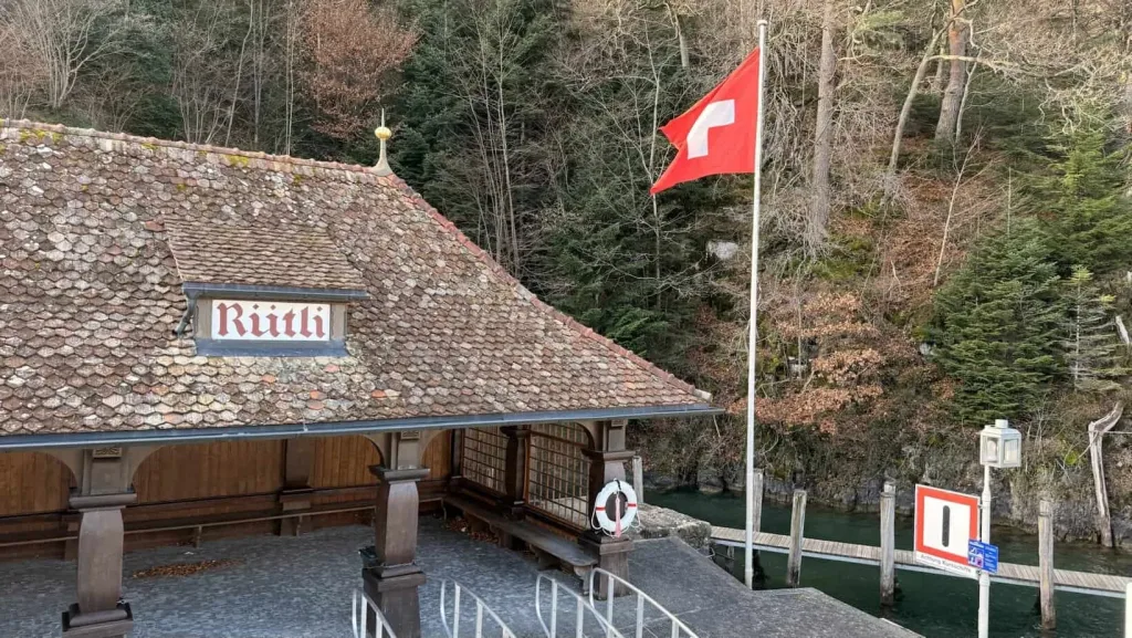 Traditionelles Schweizer Haus mit roten Ziegeln und Schweizerfahne bei Fluss in Natur.
