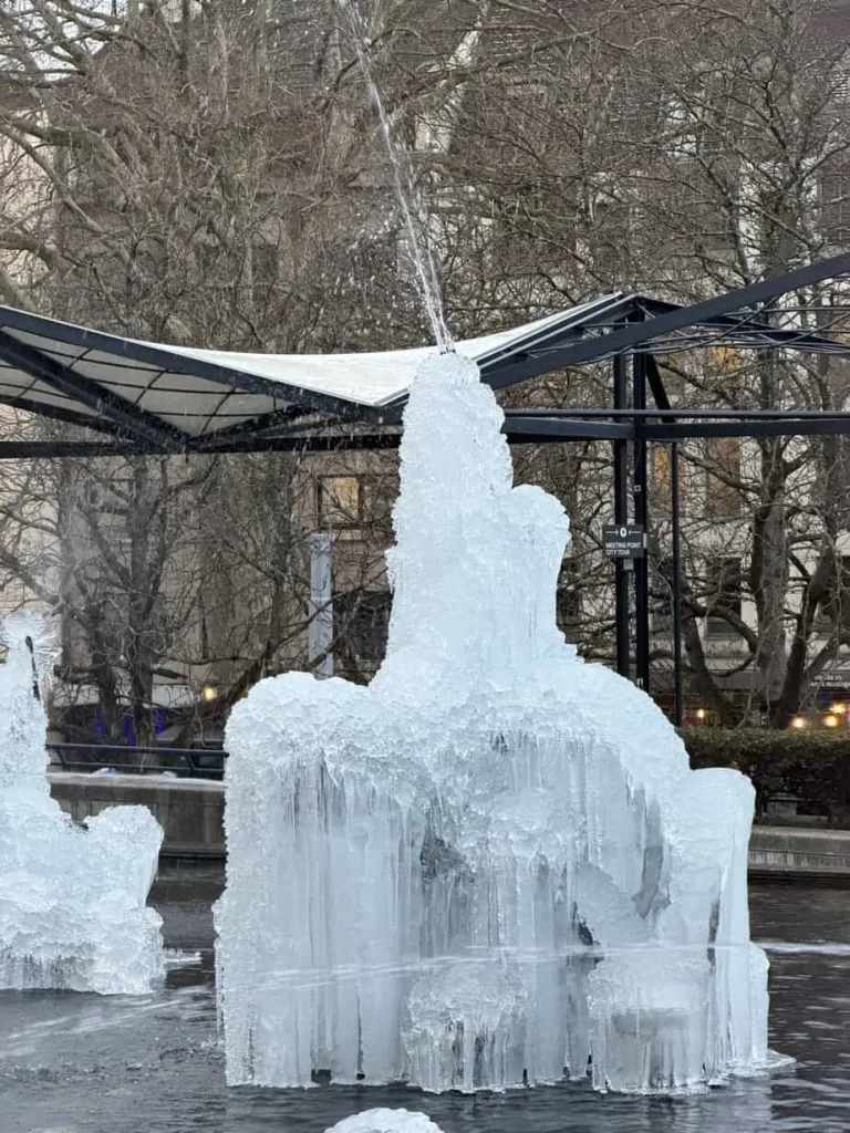 Eisskulptur im öffentlichen Park, Winterkunst, kreative Eisstatue, gefrorene Kunstinstallation, winterliche Szene.