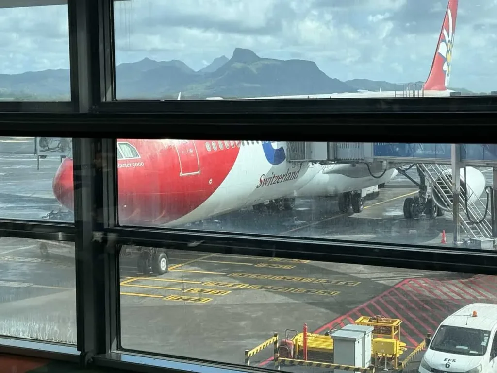 Sitzendes Flugzeug am Flughafen, mit Blick auf Berge im Hintergrund.